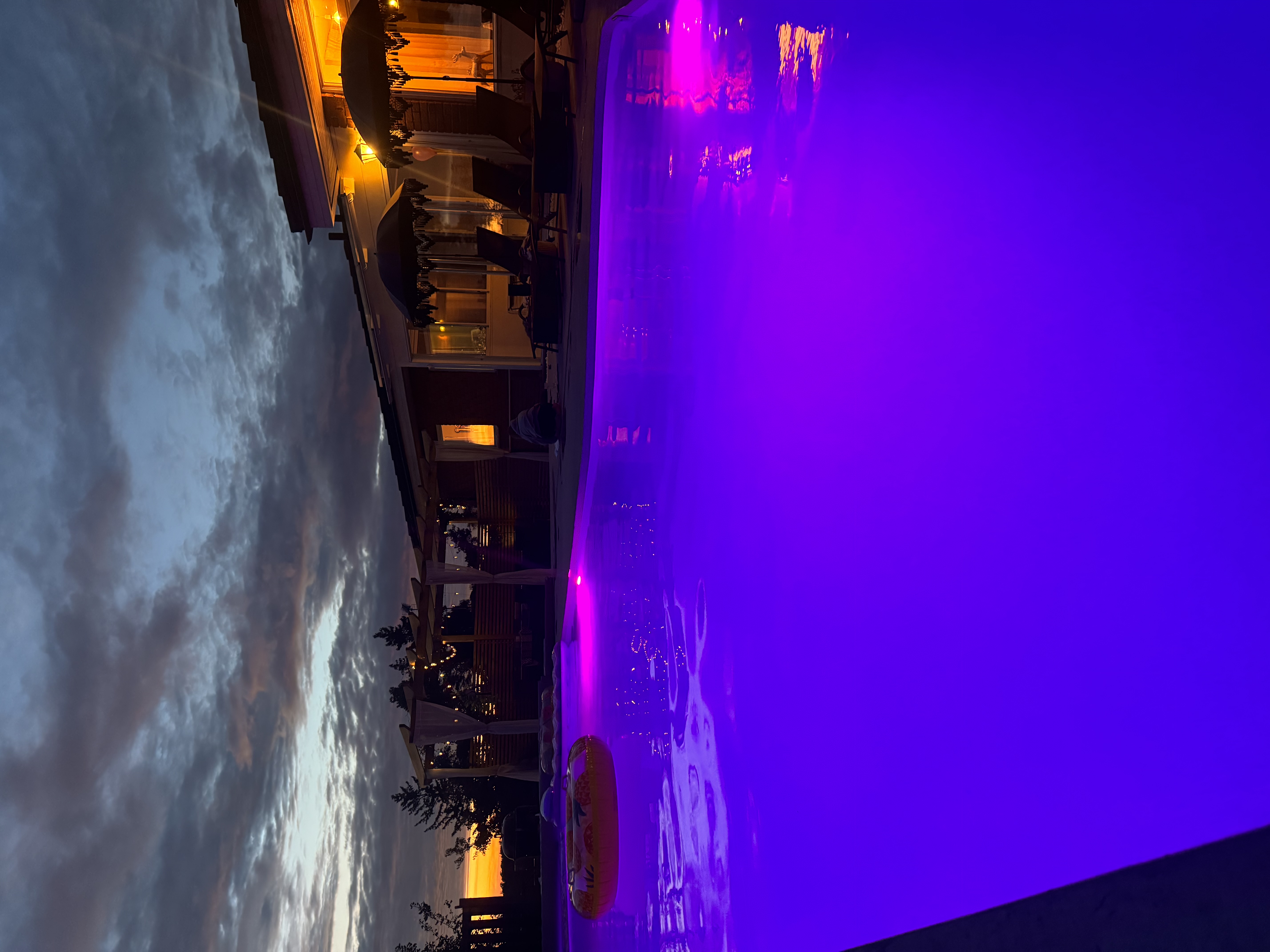 Pool med färgskiftande LED-belysning i lila och rosa töner vid kvällen – LED-renovering och modern poolbelysning