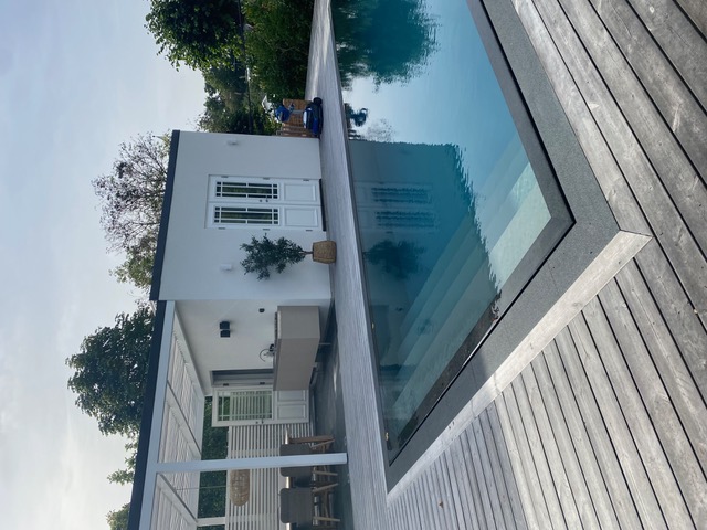 Lyxig utomhuspool med overflow-kant, modernt poolhus och pergola – design och installation